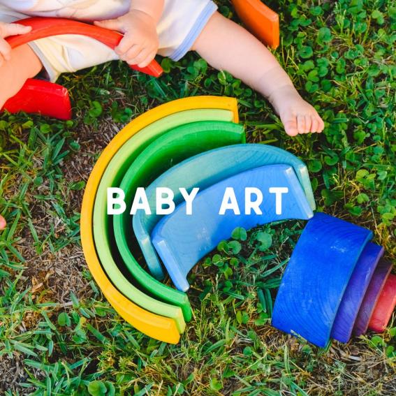 A baby on grass playing with a colourful wooden rainbow