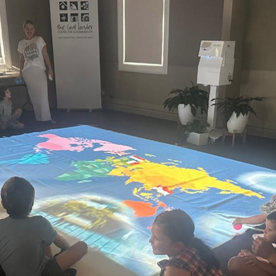 People sitting around a large floor map of the world