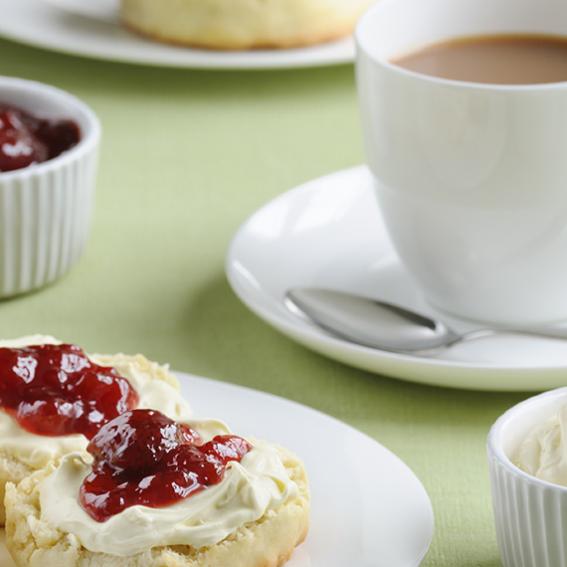 Cup of tea and a plate of scones with cream and jam