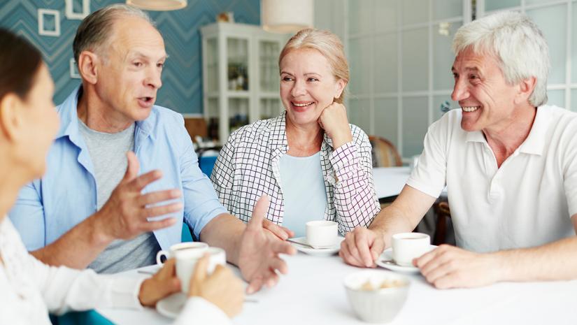 group of elderly people talking around a table