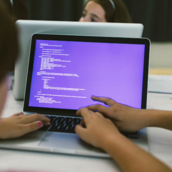 A laptop showing a purple coding screen on a white table