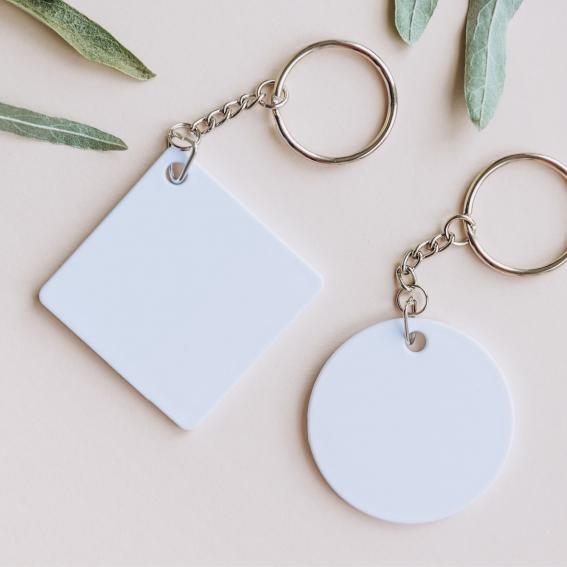 Two white key chains with leaves surrounding.