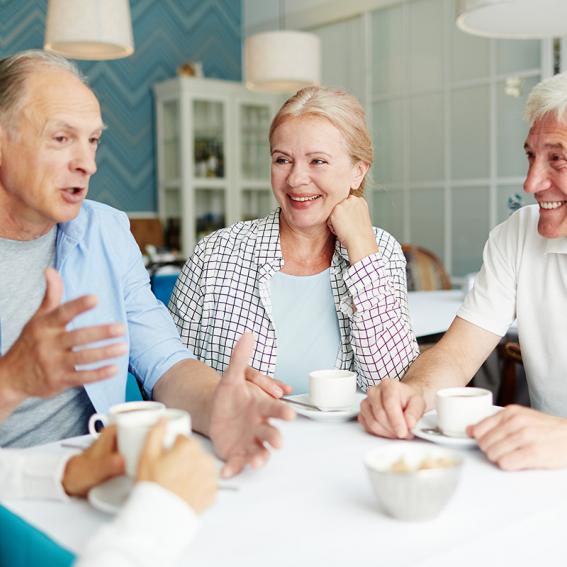 group of elderly people talking around a table