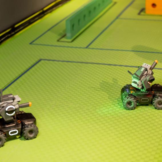 Two robots facing off on a green floor.