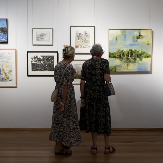 Two women looking at artwork on a wall