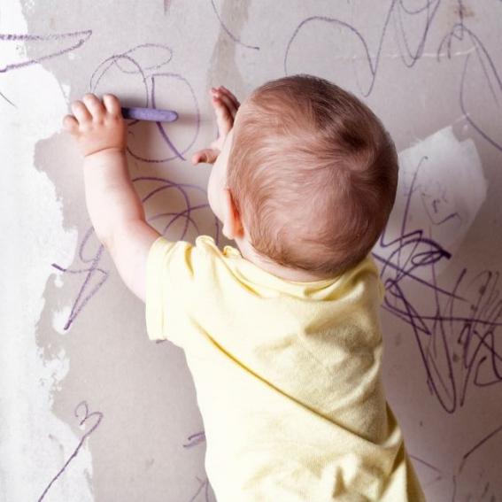 Baby drawing on a wall with crayons