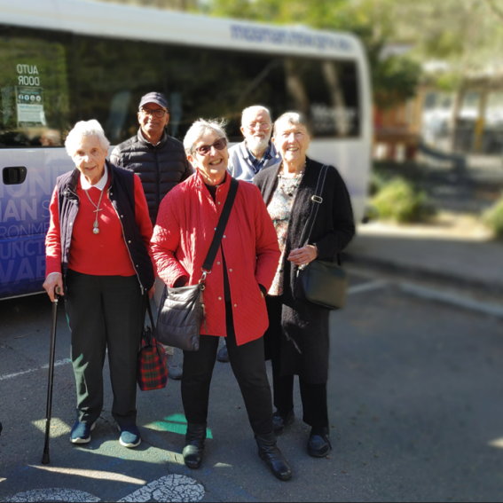 Seniors standing together next to a bus