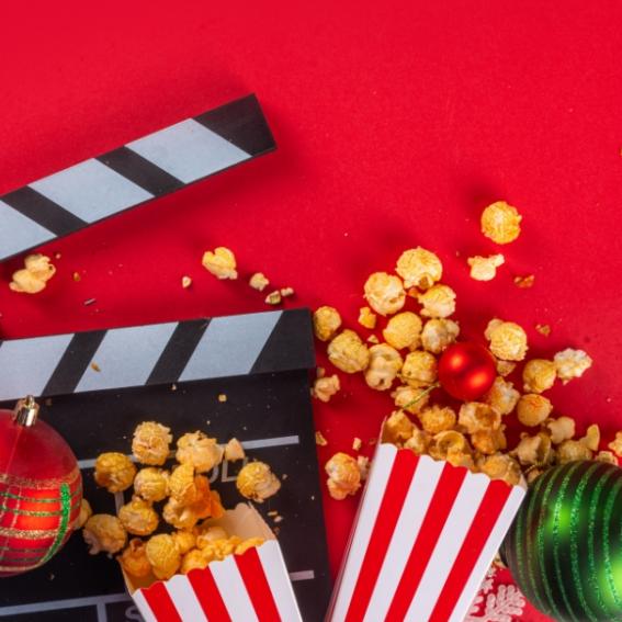 Popcorn, baubles and a clapperboard on a red background.