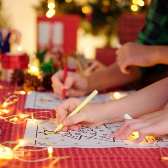 Children working on Christmas crafts on a festive table.