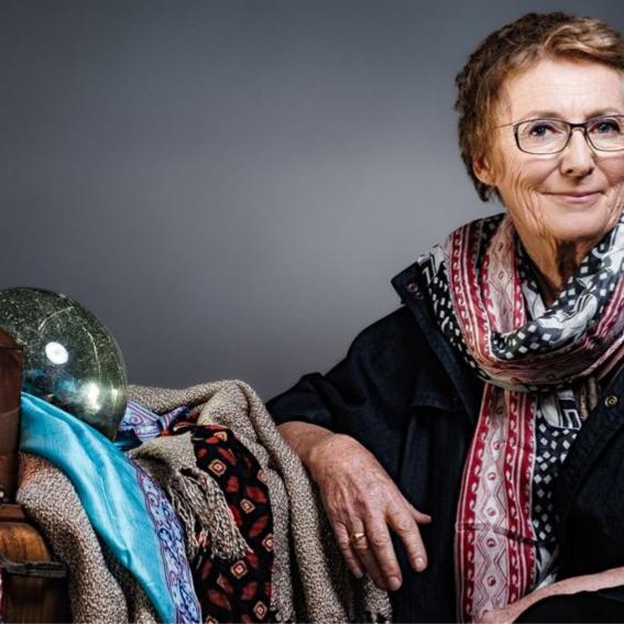 Gill Shaddick sitting, leaning on various fabrics and objects