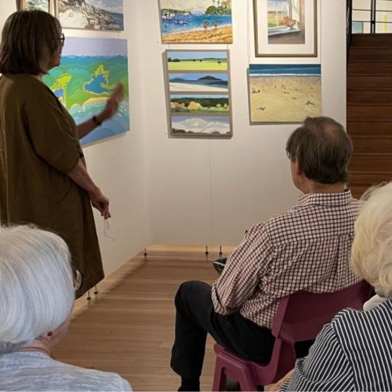 A tour guide showing an artwork to a group of viewers