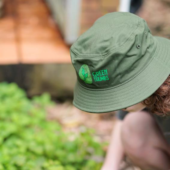 A Green Thumbs volunteers wearing a Green Thumbs hat gardening at the Centre