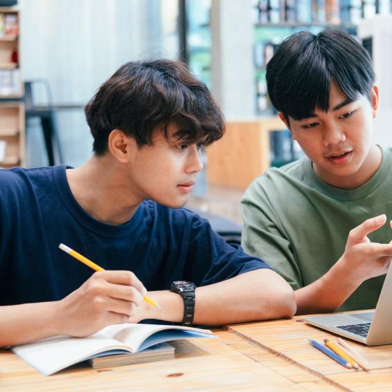 Two young men studying together at a library.