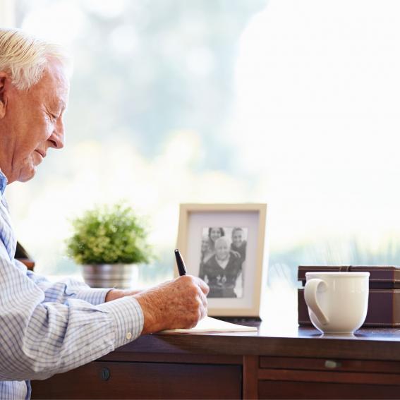 Older gentleman writing in his office.