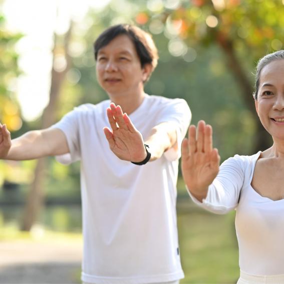 Two people practicing Qi Gong outside in a park