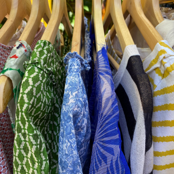 Beautiful cotton, silk and linen clothing hanging on wooden coat hangers