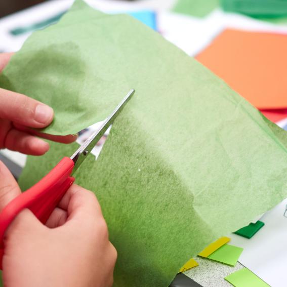 Kid cutting green paper.
