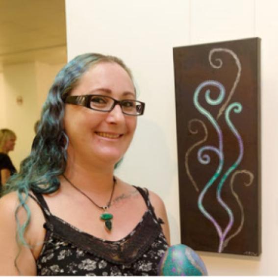 Peta-Joy Williams standing in front of Aboriginal artwork