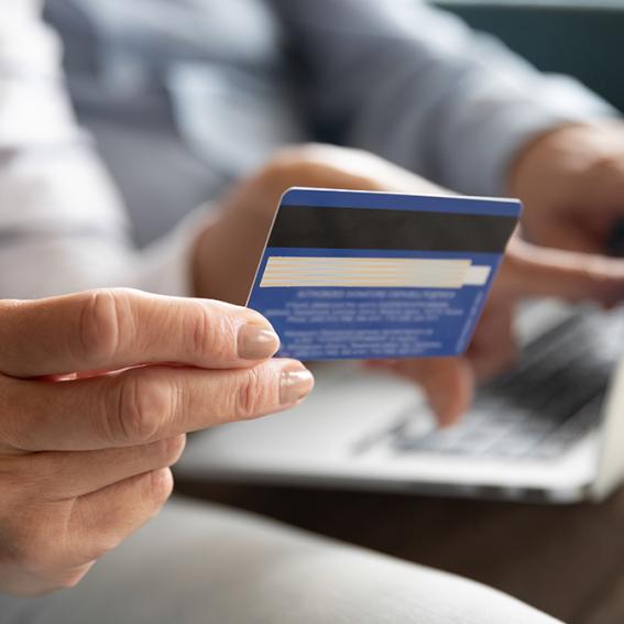 picture of a person holding a credit card whilst using a laptop