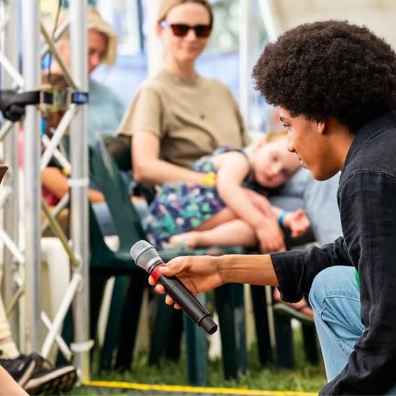 Solli Raphael holding a microphone to a young girl.