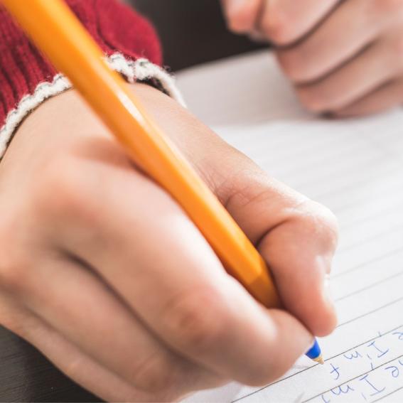 Child writing on white lined paper.