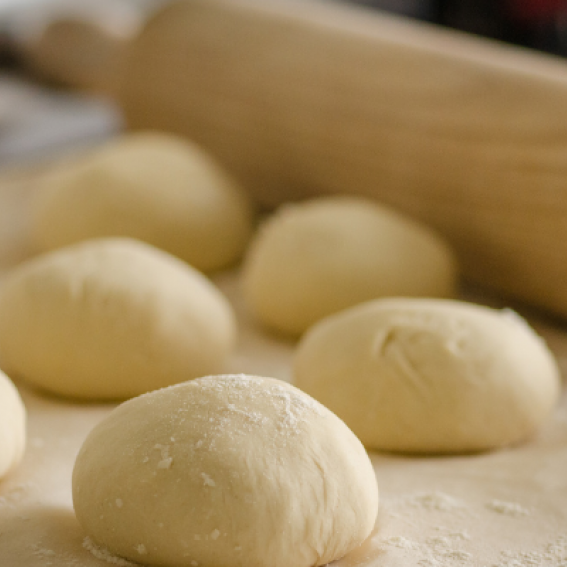 Plain dough balls covered in flour with rolling pin