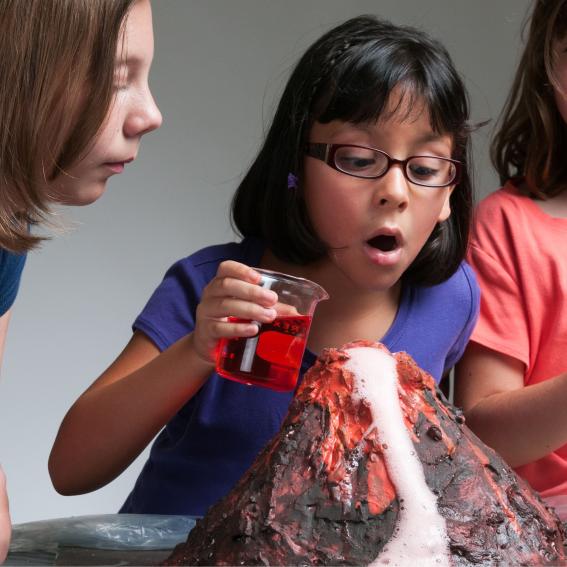 Three children working on a volcano experiment.