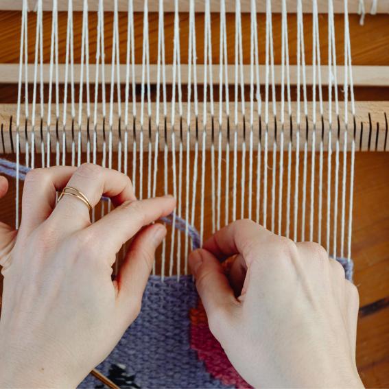 A person weaving purple yarn.