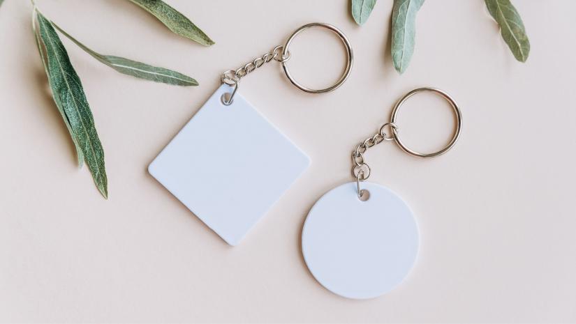 Two white key chains with leaves surrounding.