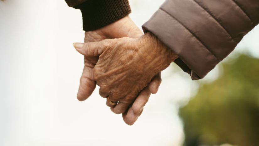 Two individuals holding hands outdoors, symbolising connection and support