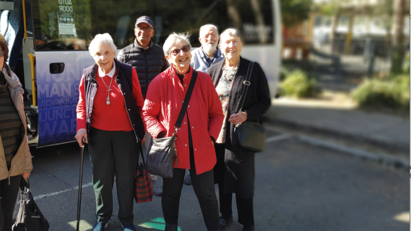 Seniors standing together next to a bus