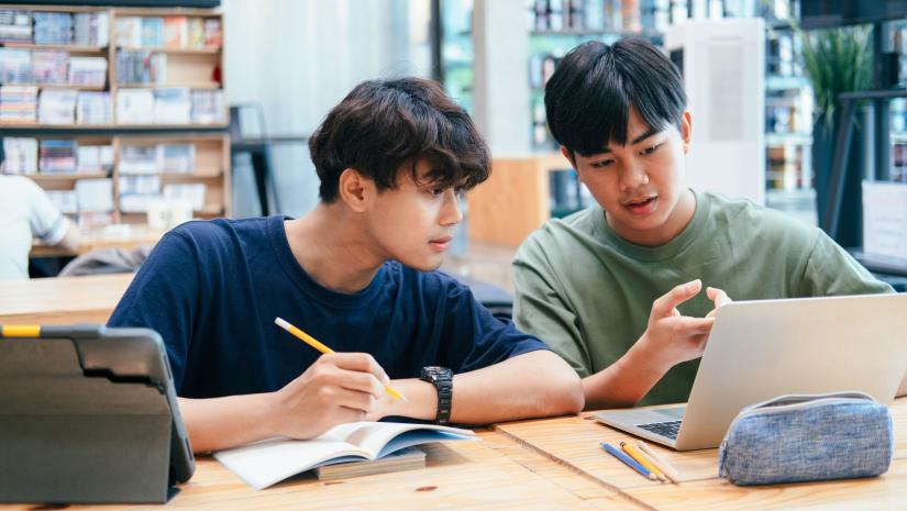 Two young men studying together at a library.