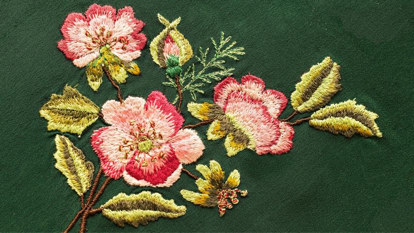 Embroidered red and yellow flowers on a green fabric