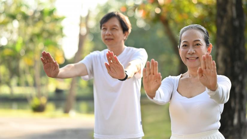 Two people practicing Qi Gong outside in a park