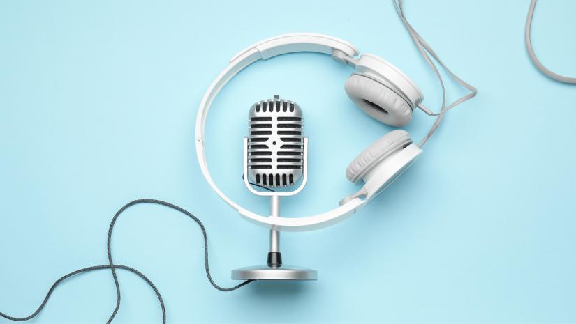 Headphones, a microphone and a cord laying down on a blue background.