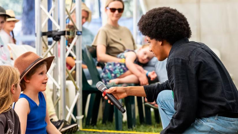 Solli Raphael holding a microphone to a young girl.