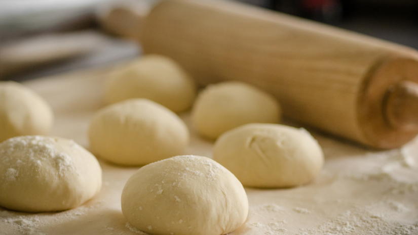 Plain dough balls covered in flour with rolling pin