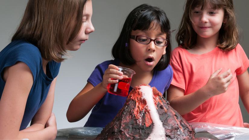 Three children working on a volcano experiment.