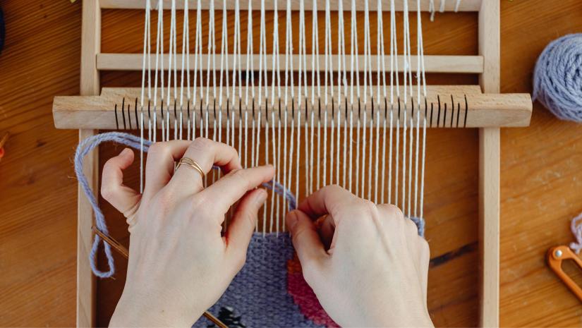 A person weaving purple yarn.